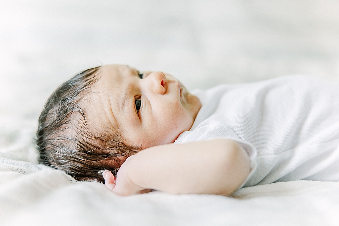 Image of professional newborn photos taken by Sara Sniderman Photography, a family, newborn and maternity photographer serving the Metro West Boston area include: Natick, Needham, Newton, Wellesley, Wayland, Weston, Sherborn, Sudbury, Southborough, Medfield, Medway, Holliston, Framingham. Image shows baby laying on a bed. 