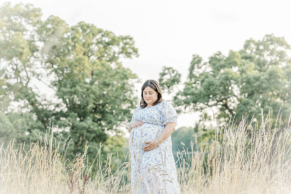 Pregnant woman stands in filed of grass during maternity photo session in Needham Massachusetts with Sara Sniderman Photography