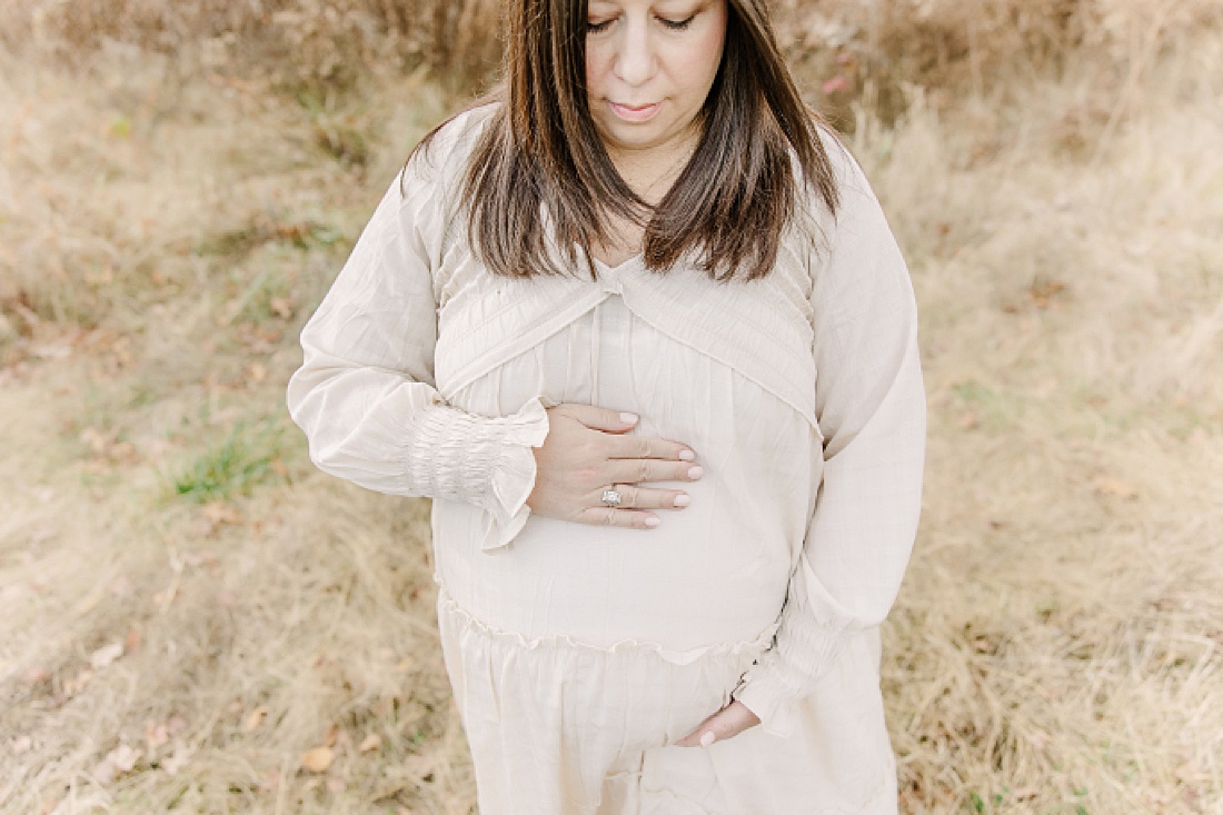 pregnant woman stands in field during maternity photo session with Sara Sniderman Photography in Needham Massachusetts