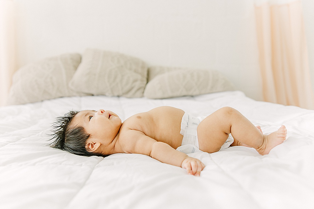 baby lays on bed during studio lifestyle photo session with Sara Sniderman Photography in Natick Massachusetts