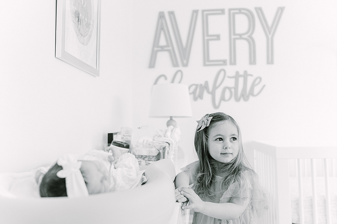 black and white of big sister looking at baby during in-home newborn photo session with Sara Sniderman Photography in Needham Massachusetts