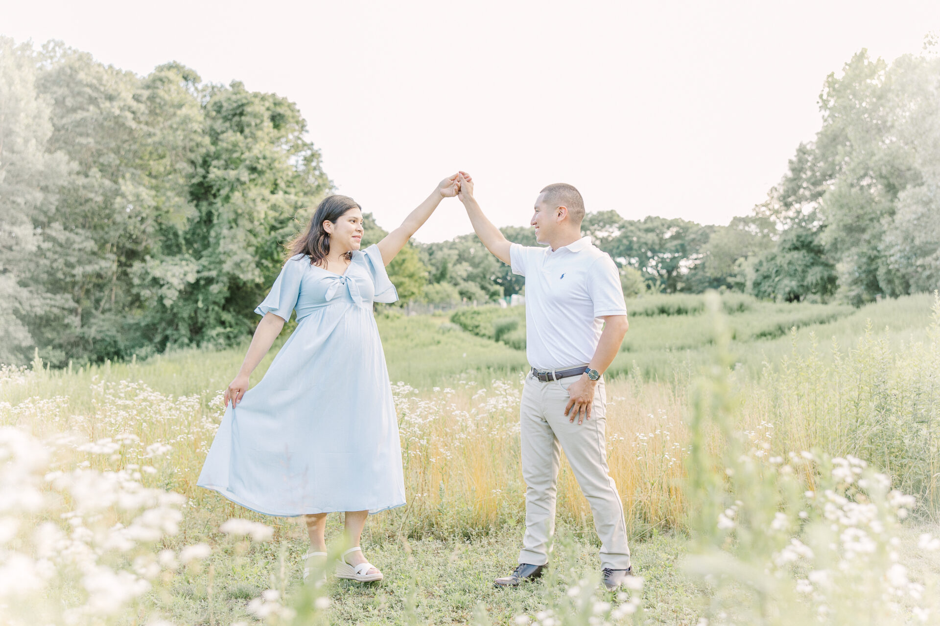 husband twirls wife during maternity photo session with Sara Sniderman Photography in Newton Massachusetts