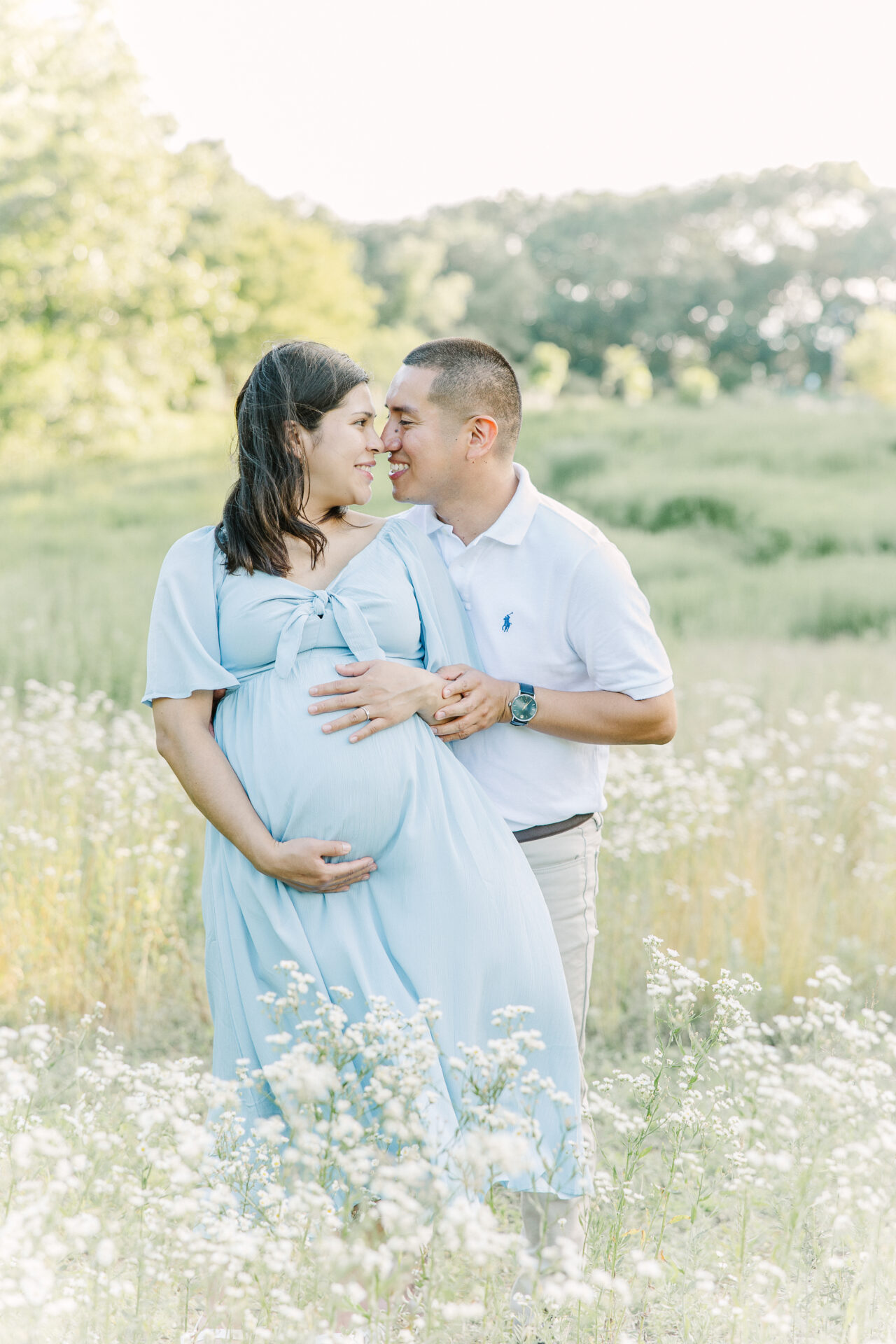 couple kiss in field of flower during maternity photo session with Sara Sniderman Photography in Newton Massachusetts