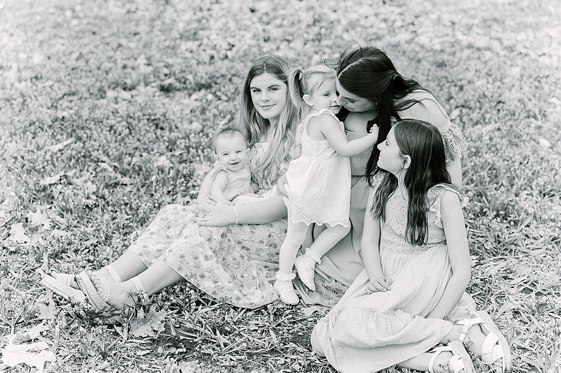 black and white of mom in field of flowers with her four daughters during first birthday photo session with Sara Sniderman Photography in Wellesley Massachusetts