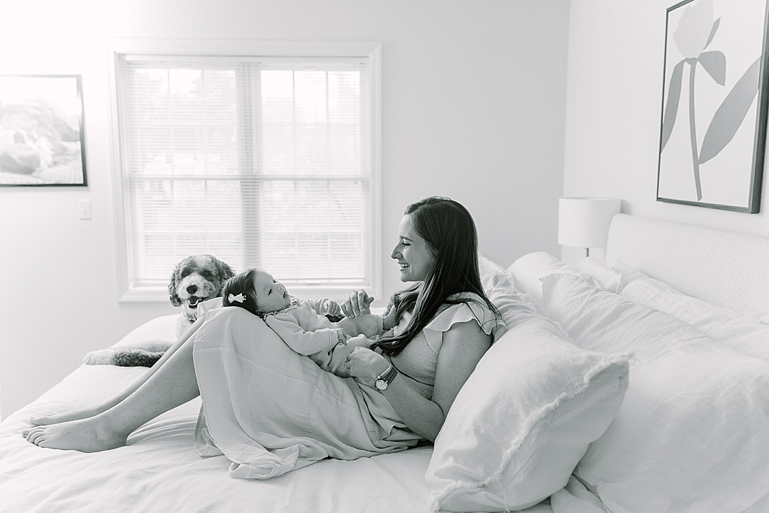 black and white photo of mom on bed with baby during in-home newborn photo session with Sara Sniderman Photography in Norwood Massachusetts