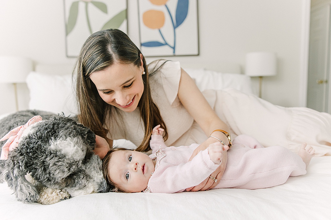 mom and dog lay with baby during in-home newborn photo session with Sara Sniderman Photography in Norwood Massachusetts