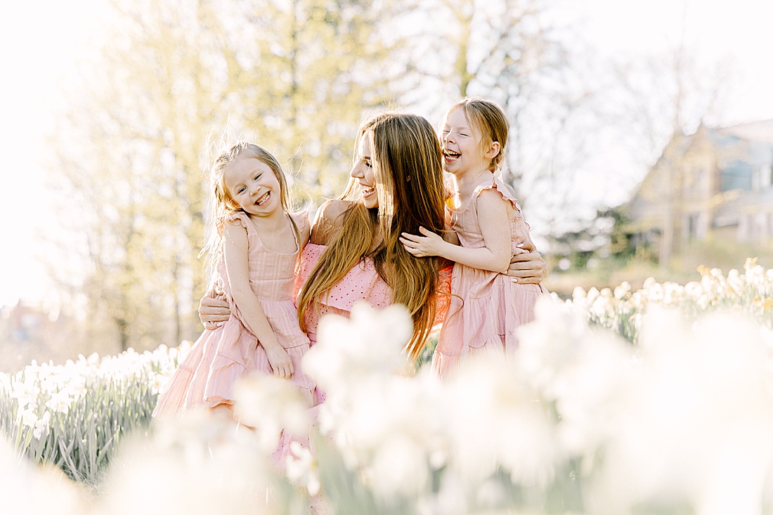mother cuddles with daughters during family photo session with Sara Sniderman Photography at Wellesley College. 