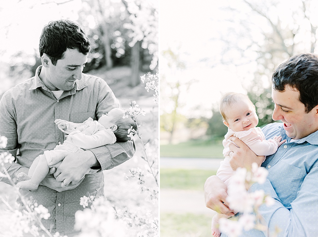 dad holds baby by flowering tree uring family photo session with Sara Sniderman Photography at Wellesley College.