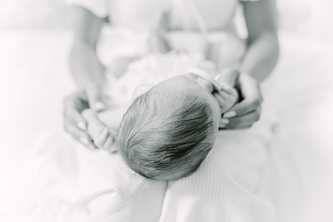 black and white of babies head on mothers lap during in-home newborn photo session with Sara Sniderman Photography in Natick Massachusetts