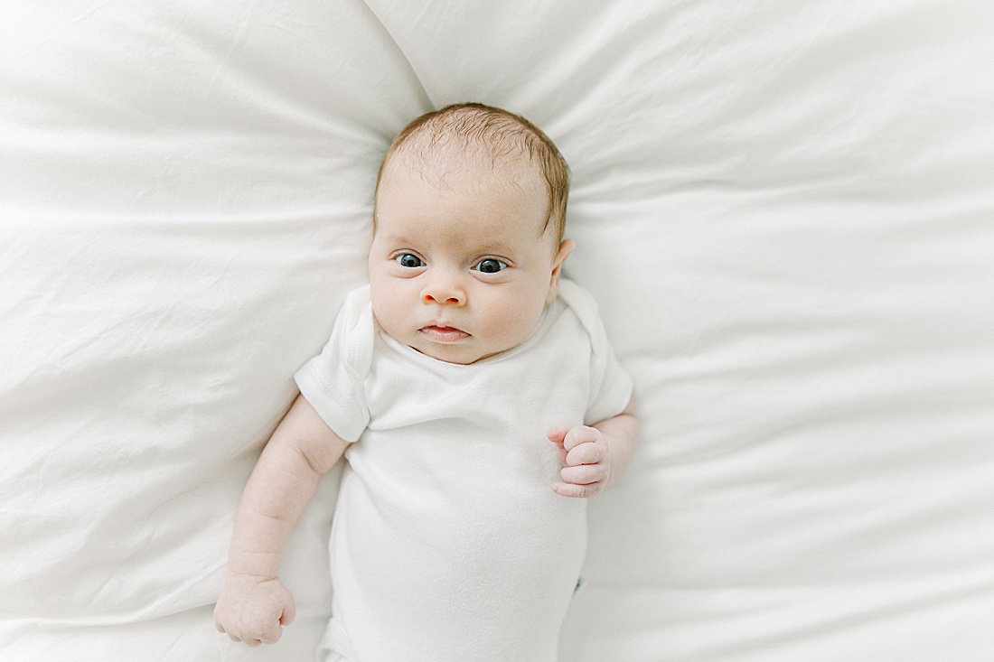 baby lays on bed during in-home newborn photo session with Sara Sniderman Photography in Natick Massachusetts