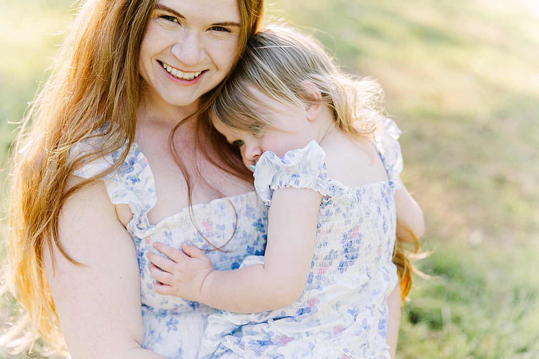 mother hugs daughter during summer family photos with Sara Sniderman Photography t Heard Farm in Wayland Massachusetts. 