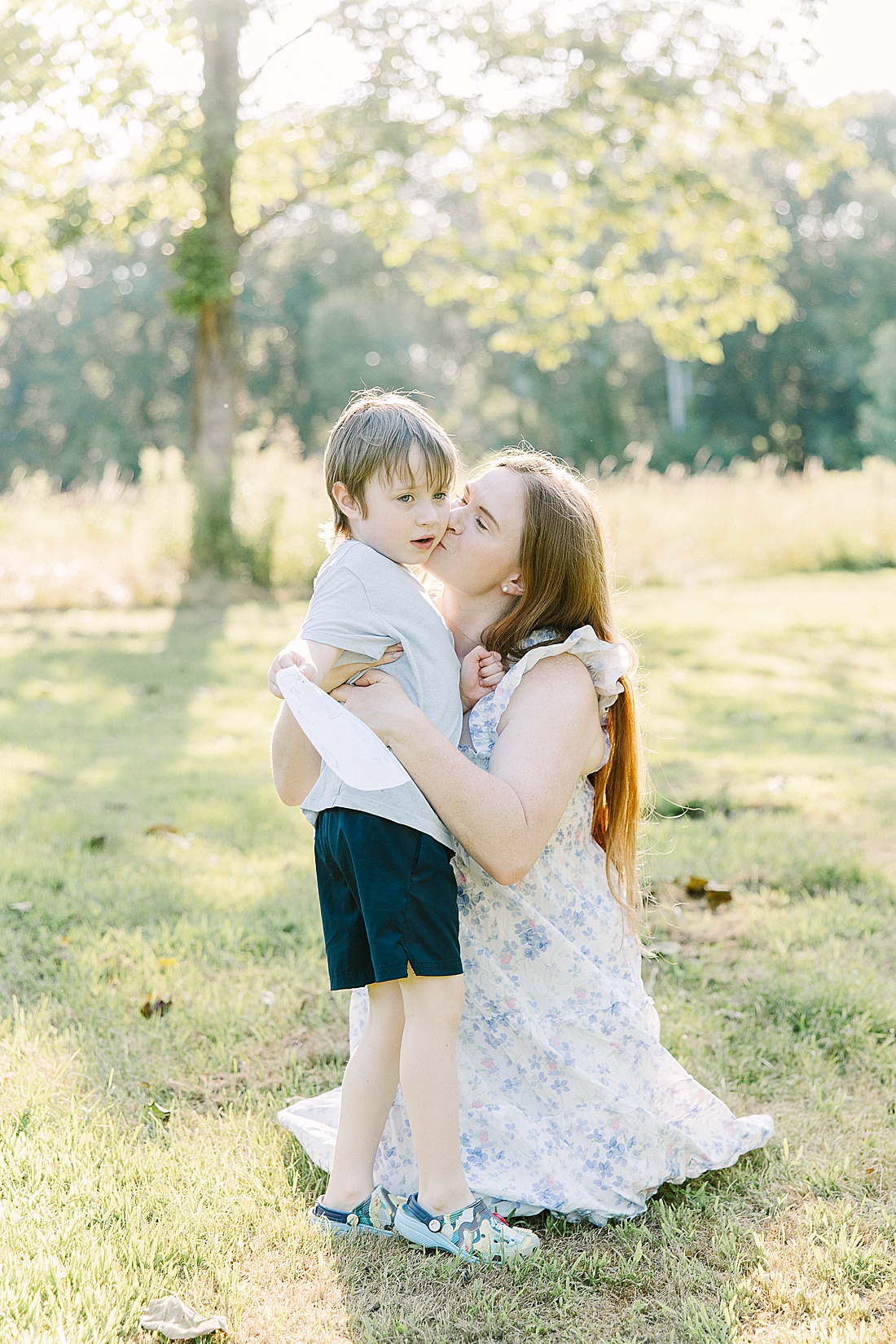 mother kisses son during summer family photos with Sara Sniderman Photography t Heard Farm in Wayland Massachusetts. 