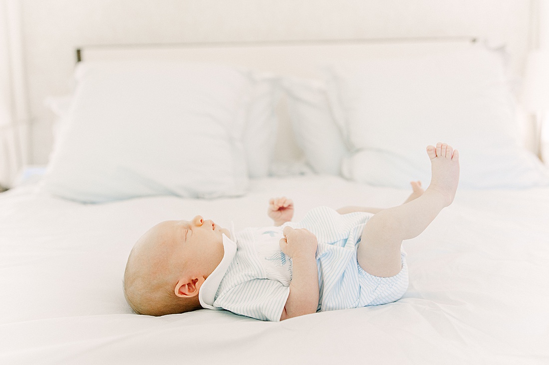 baby lays on bed during in-home newborn photo session with Sara Sniderman Photography in Wellesley Massachusetts. 