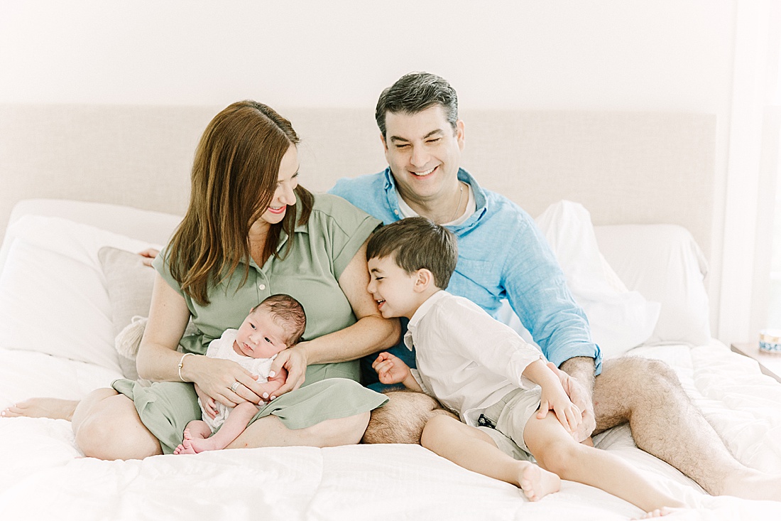 family cuddles on bed during in-home newborn photo session with Sara Sniderman Photography in Sherborn Massachusetts