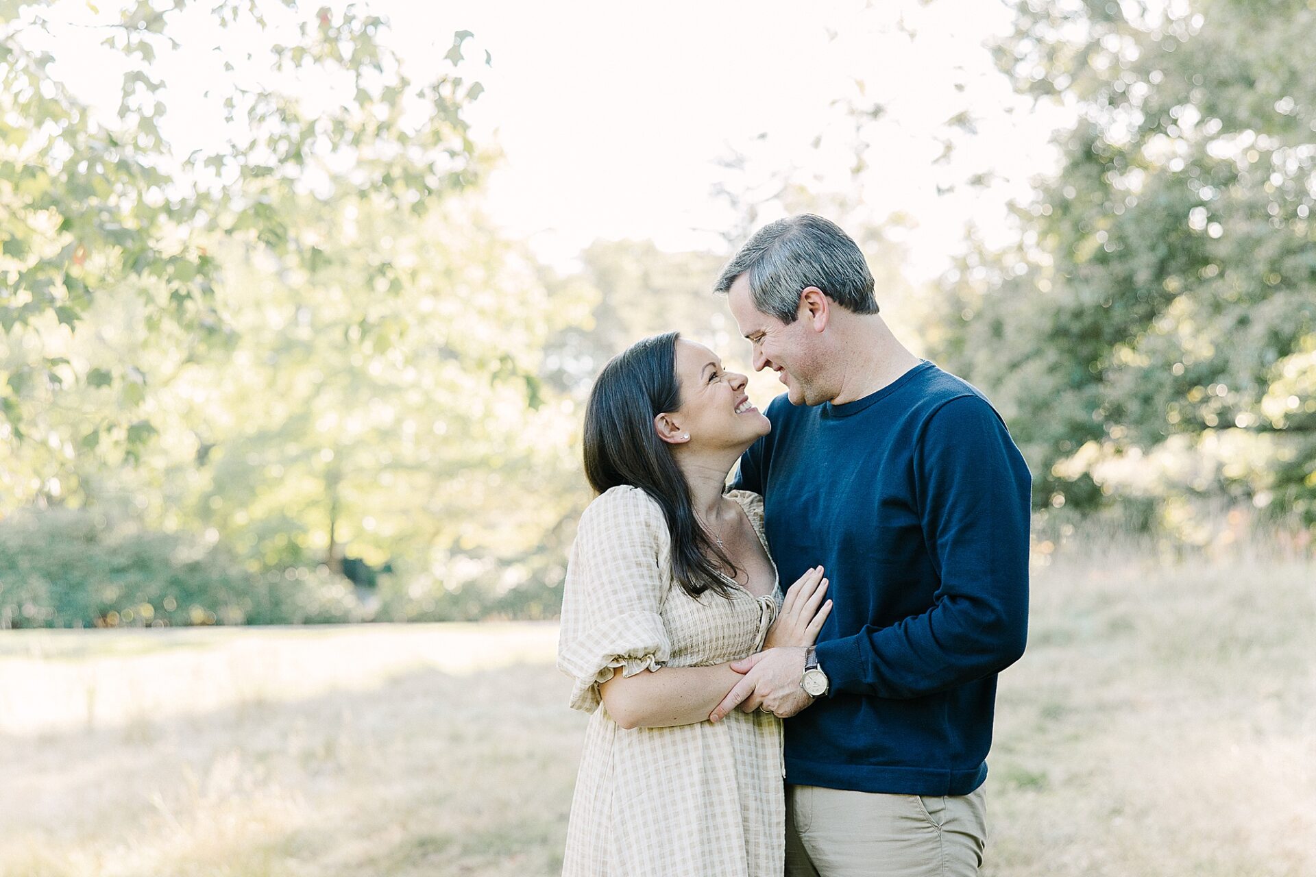 parents smile at each other during outdoor newborn photo session with Sara Sniderman Photography at Wellesley College