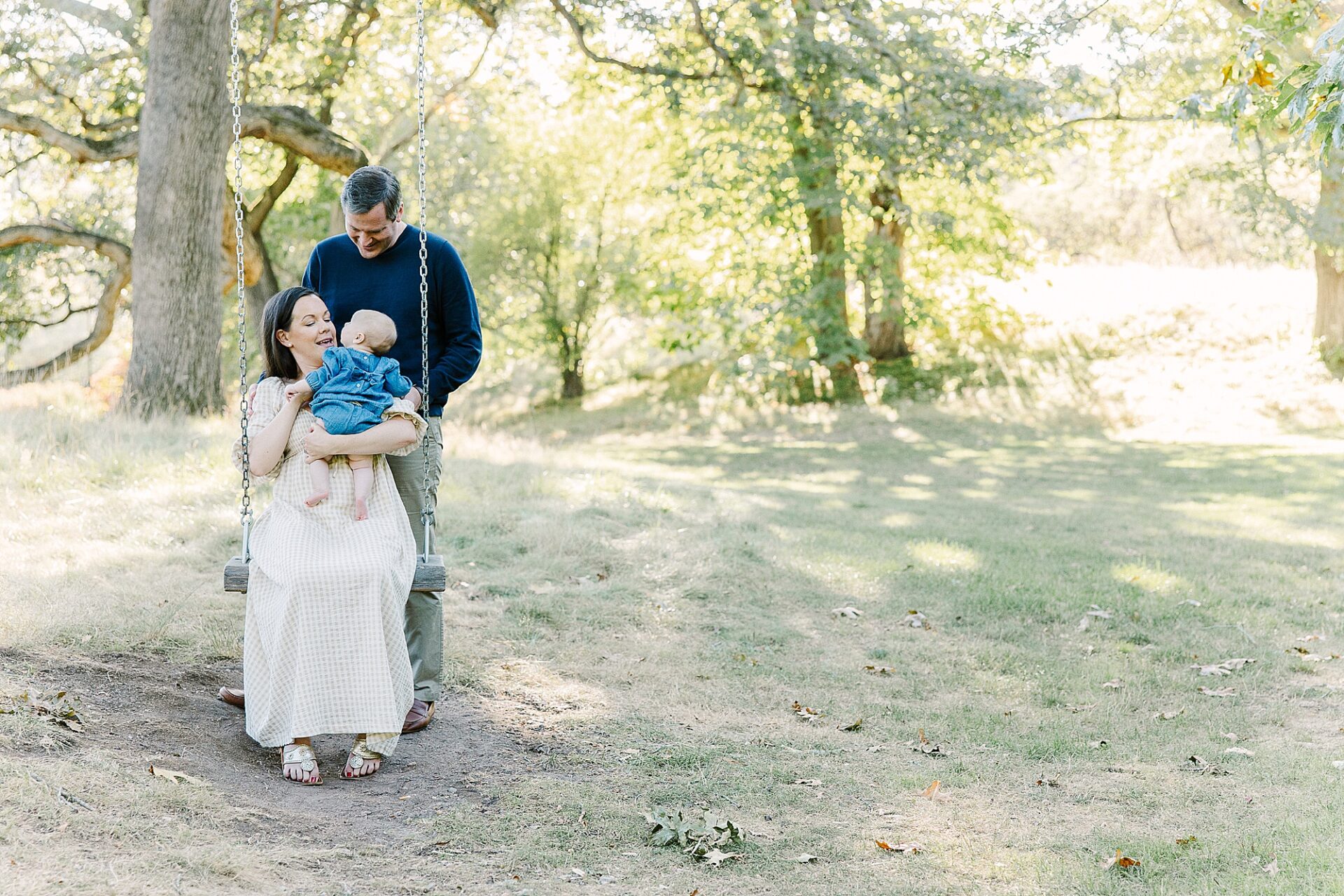 family on tree swing during outdoor newborn photo session with Sara Sniderman Photography at Wellesley College