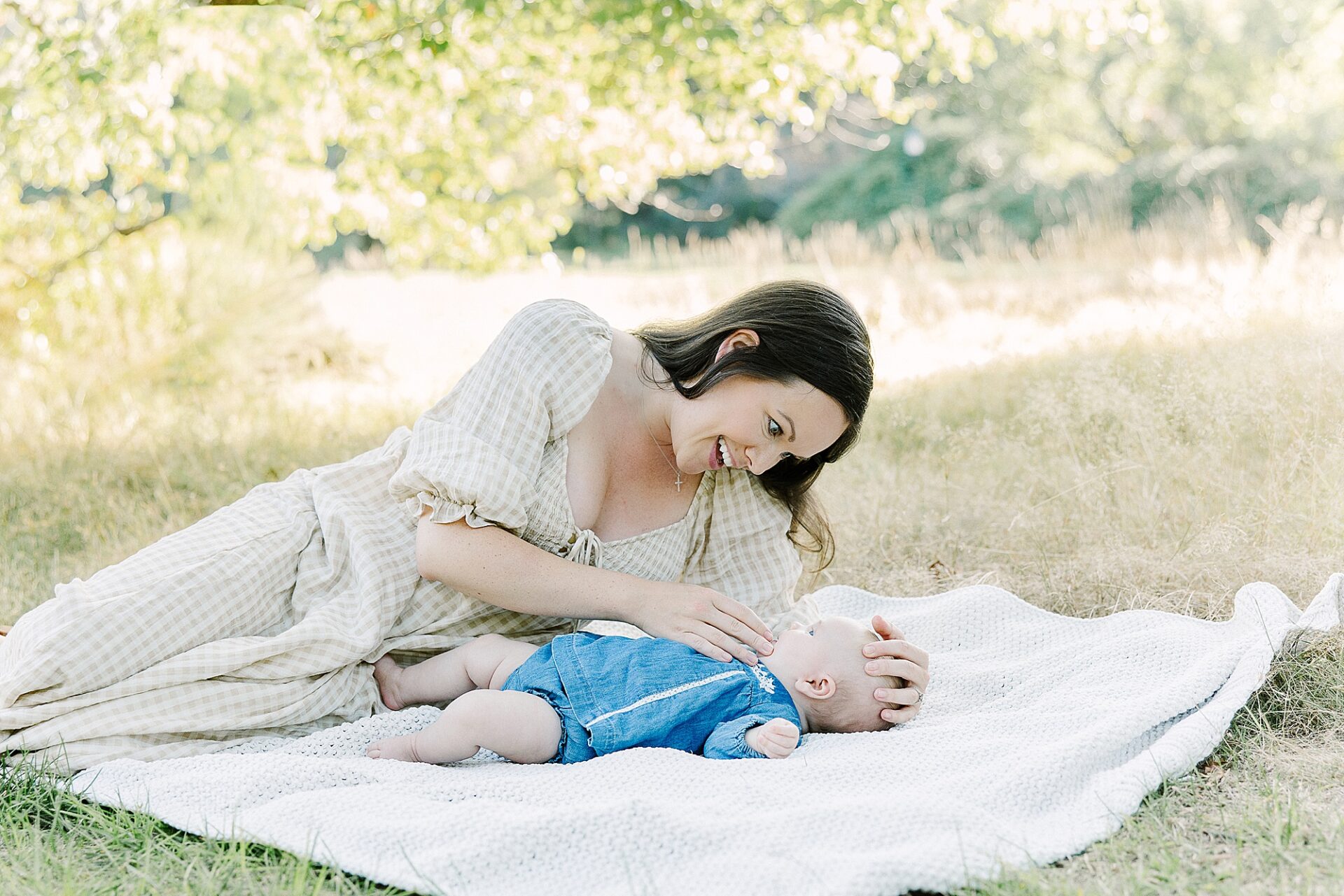 mother and baby lay on blanket during outdoor newborn photo session with Sara Sniderman Photography at Wellesley College