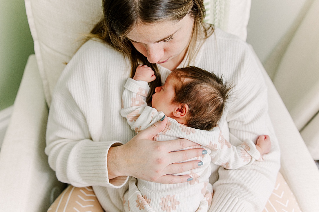 mother holds newborn in rocking chair during in-home newborn photo session with Sara Sniderman Photography in Natick Massachusetts