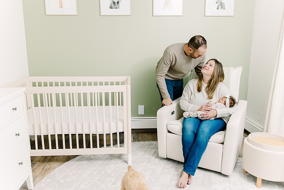 parents and dog sit in nursery during in-home newborn photo session with Sara Sniderman Photography in Natick Massachusetts