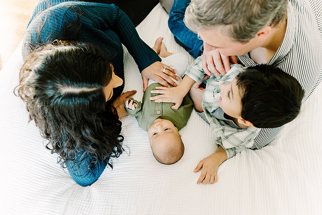family cuddles on bed during in-home newborn photo session with Photographer Sara Sniderman in Metro West Boston. 
