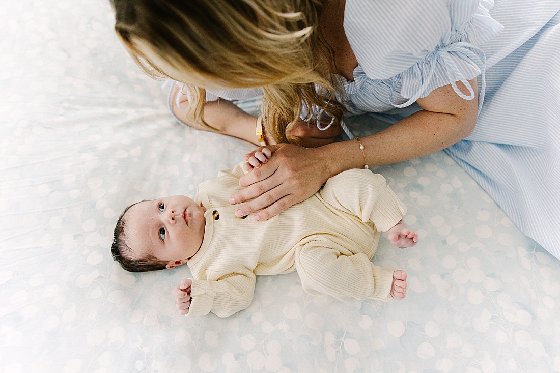 mom lays on bed with baby during in home newborn photo session with Sara Sniderman Photography in Holliston Massachusetts