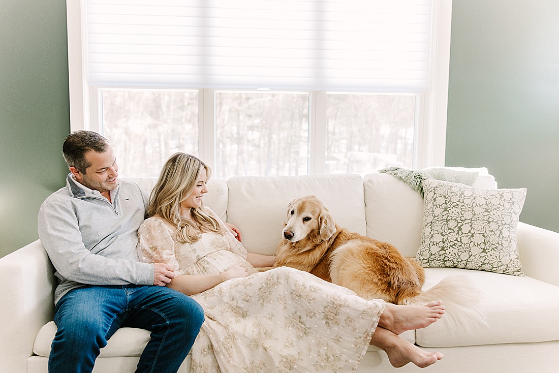 couple and dog sit on couch during in home maternity photo session with Sara Sniderman Photography in Holliston Massachusetts