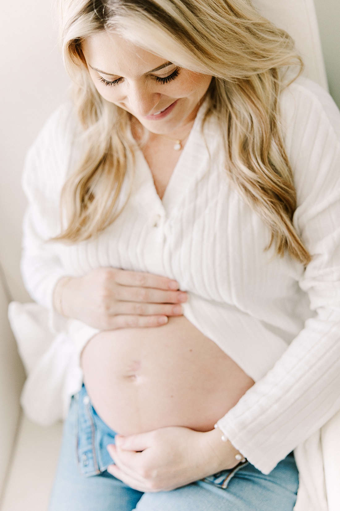woman holds belly during in home maternity photo session with Sara Sniderman Photography in Holliston Massachusetts