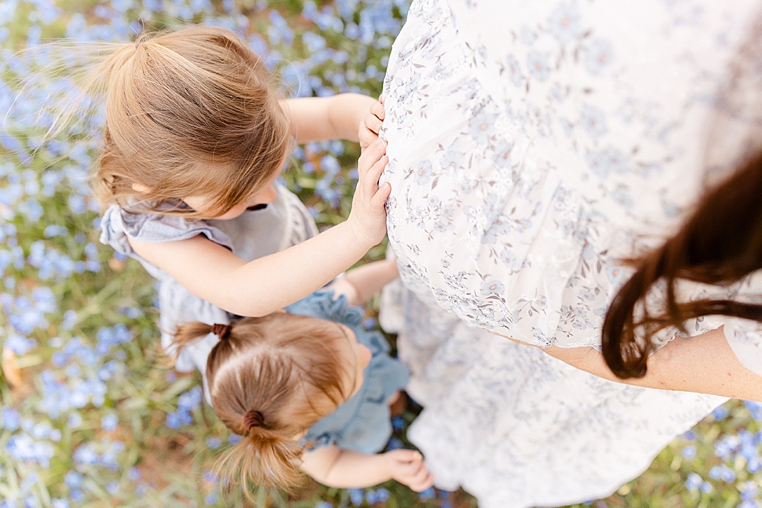 toddlers touch others pregnant belly during maternity photo session at Wellesley College with Sara Sniderman Photography